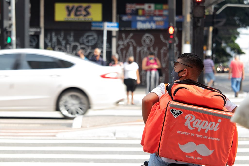 A man delivering food and crossing the street in a busy city.
