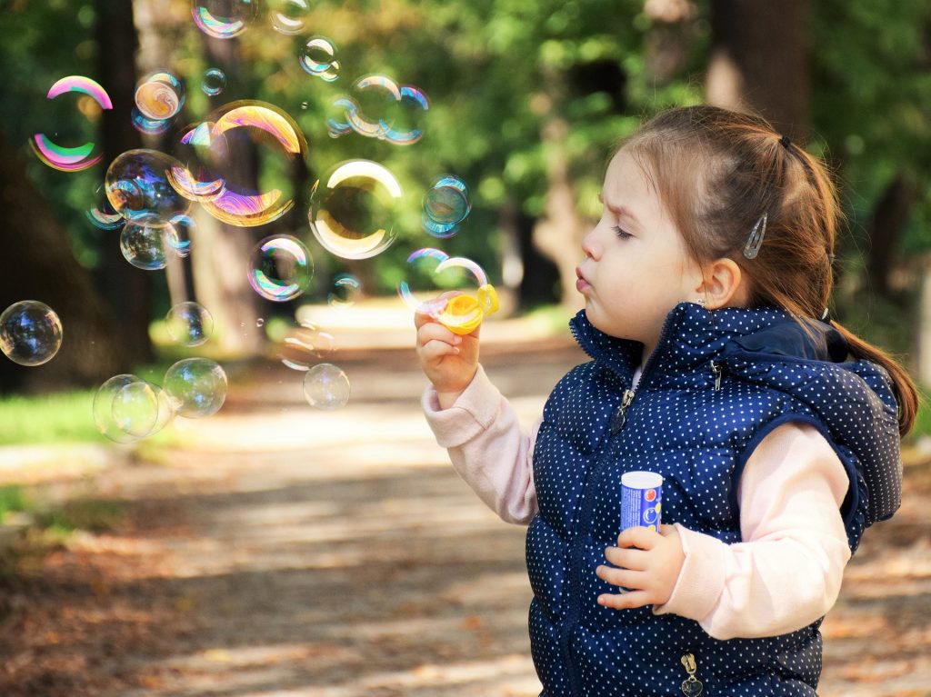 A little girl blowing bubbles.