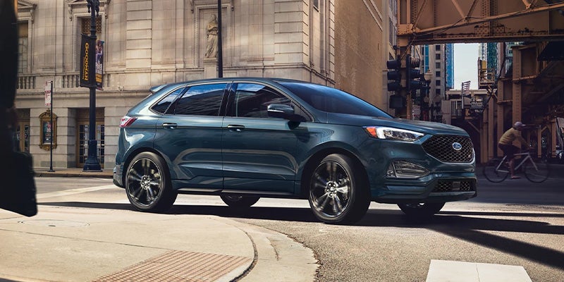 A blue 2023 Ford Edge turning a corner.