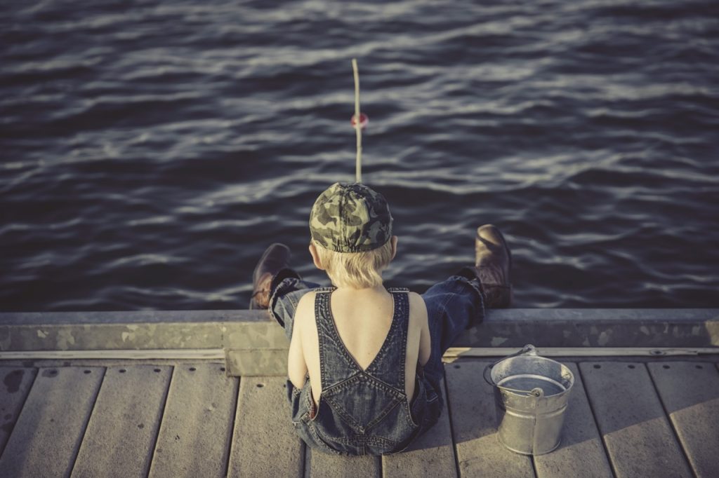 A little kid fishing on a dock.