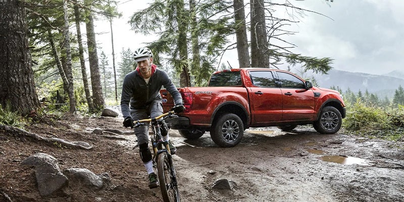 A red 2023 Ford Ranger and its owner on a bike.