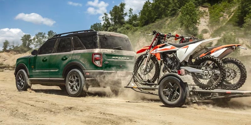 A green 2024 Ford Bronco Sport towing dirt bikes.