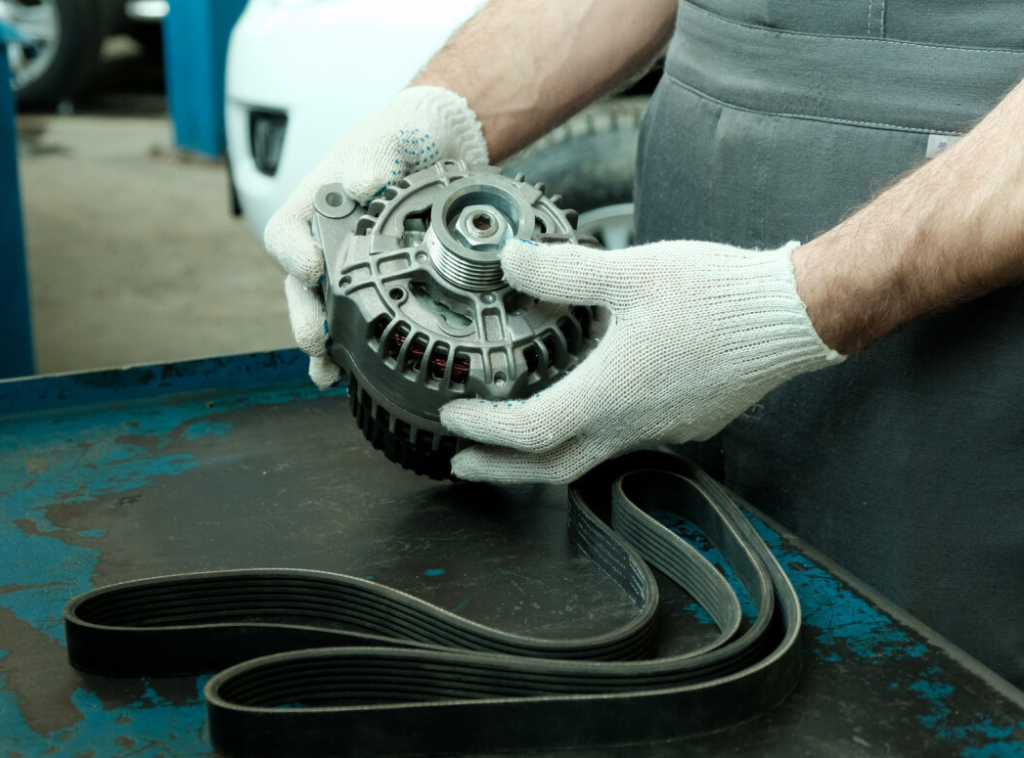 An auto repair technician holding a vehicle alternator.