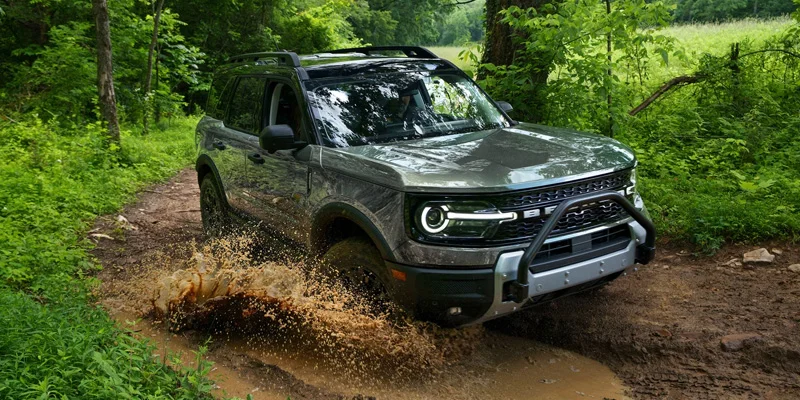 A Ford Bronco Sport driving through a muddy trail, showcasing its off-road capabilities.