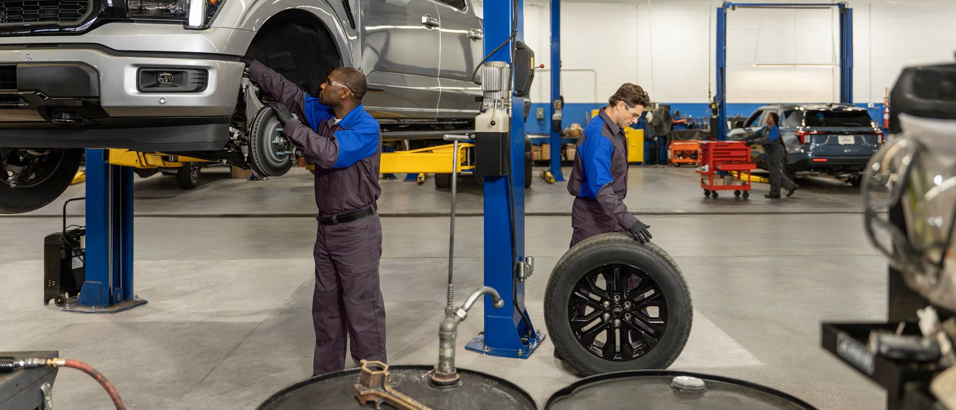 Automotive technicians servicing a vehicle and inspecting tires in a repair shop